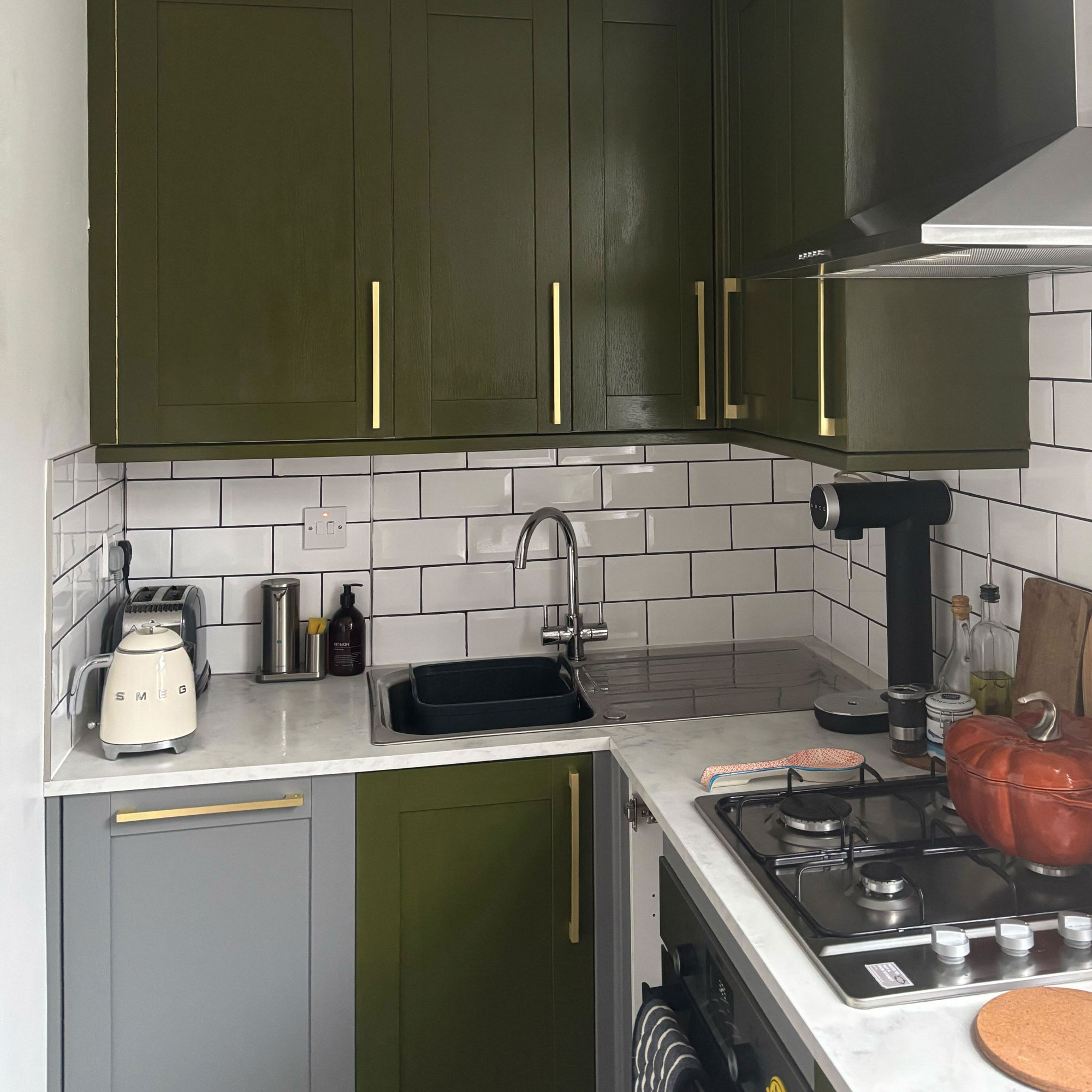 Green painted kitchen with gold handles and white countertops