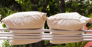 Pillows outside on an airer after being washed, drying in the sunshine to show how to was pillows properly