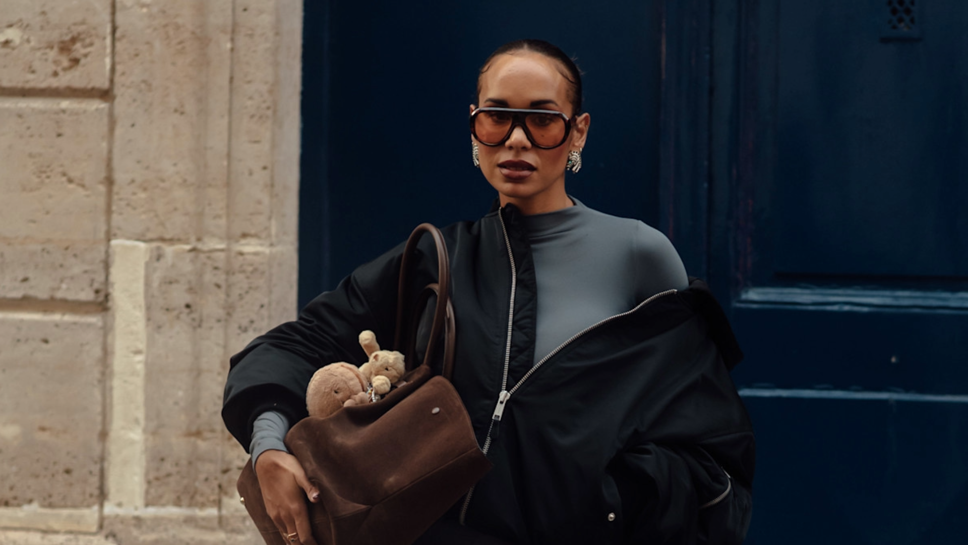 woman wearing sunglasses and a jacket with a gray turtleneck dress.