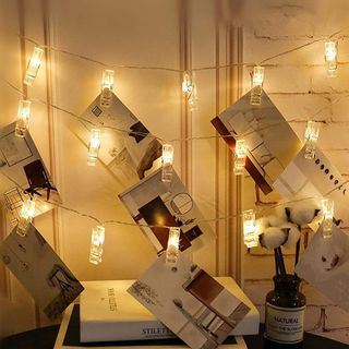 Three rows of picture clip string lights with pictures hanging from it.