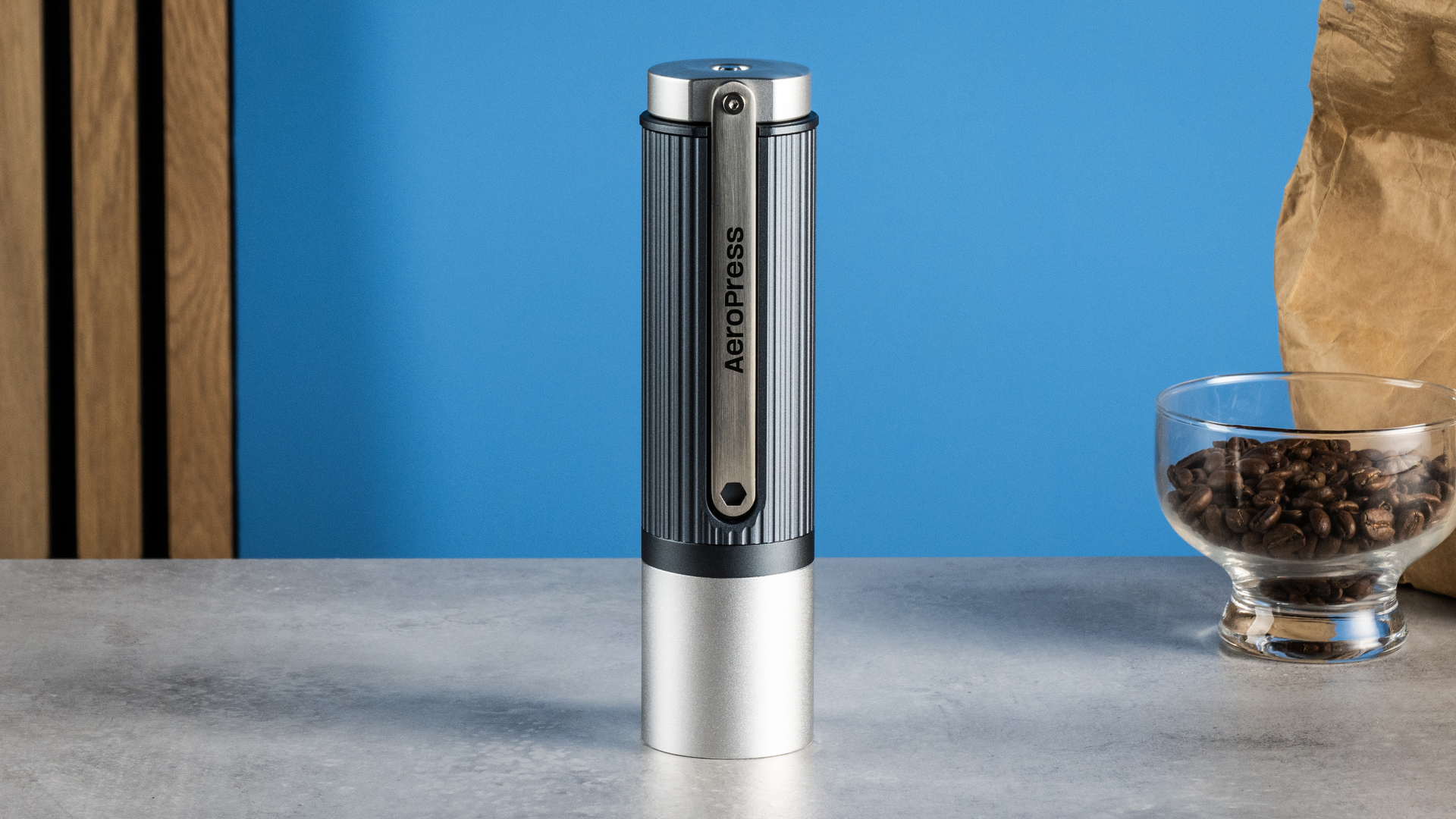 the aeropress manual coffee grinder in gray and silver against the tom's guide blue background