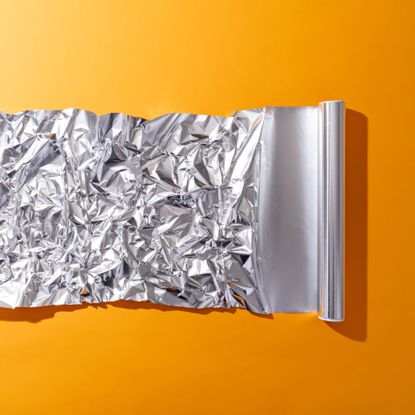 Roll of tin foil on orange background