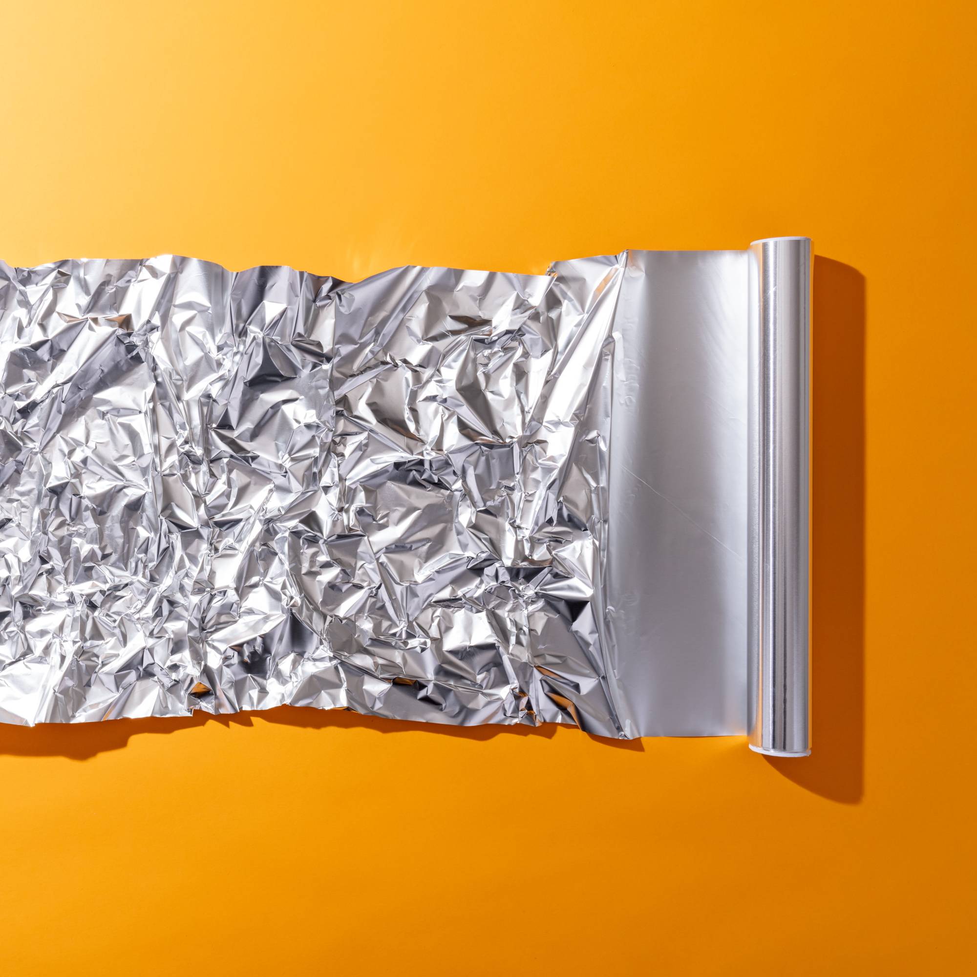 Roll of tin foil on orange background