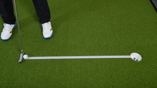 PGA pro Ged Walters trying to putt a golf ball along a ruler