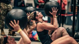 A woman performing sit-up medicine ball throws at DEKA