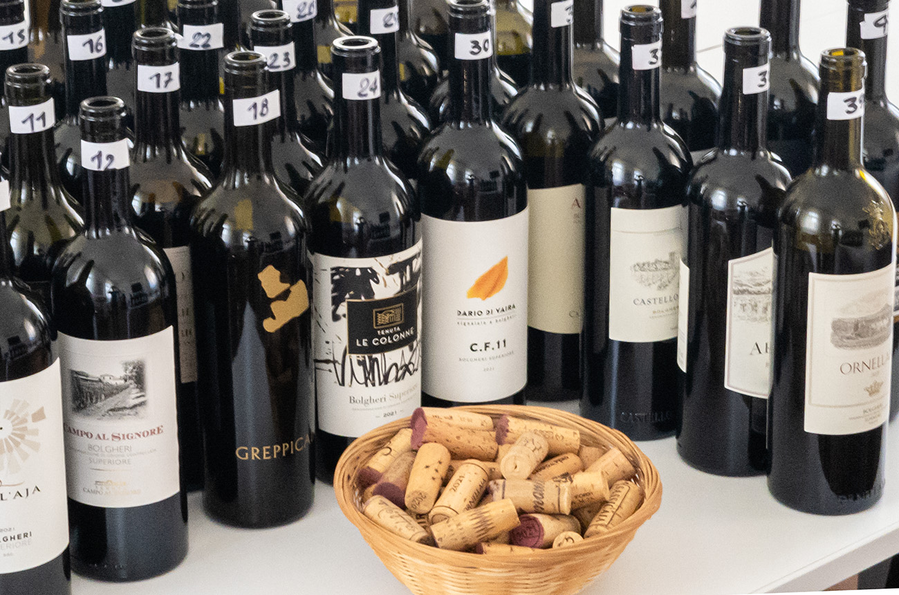 Bottles of Bolgheri Superiore 2021 and a basket of wine corks