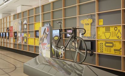 Great Britain Cycling Team Olympic track bike, 2012 on display on a stand infrom of wall shelves with TVs and information