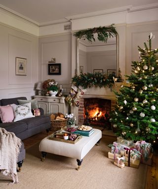 traditional-style living room with grey corner sofa and christmas tree with fire lit