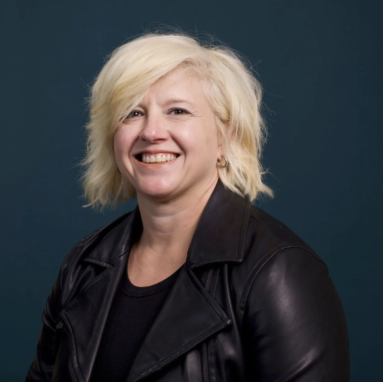 A headshot of a woman with cropped blonde hair