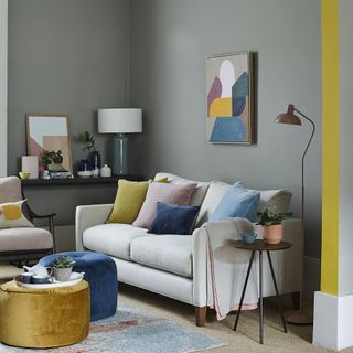 living room with grey painted wall and sofa with colourful cushions
