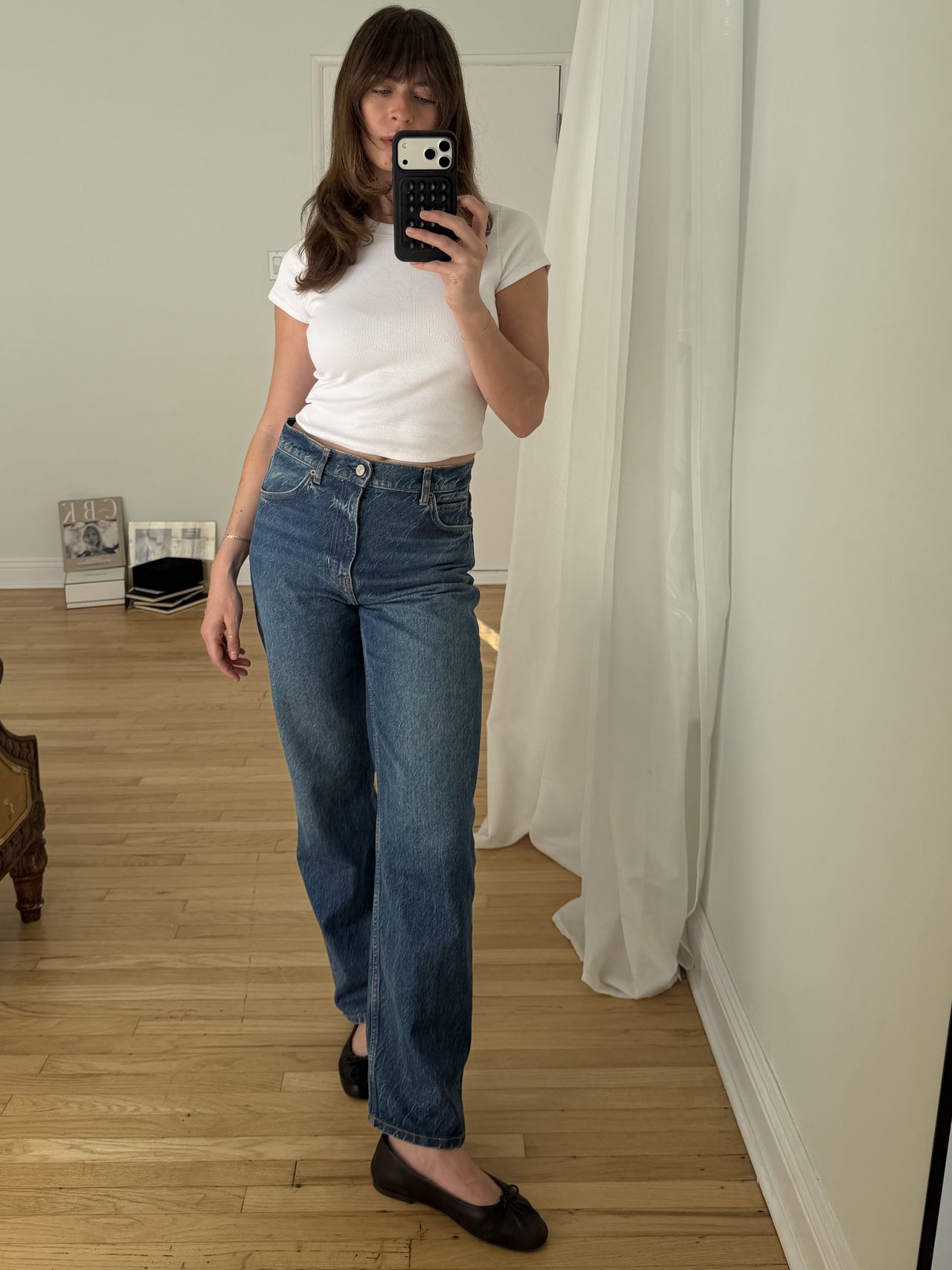 Kathryn Zahorak posing in mirror wearing white t-shirt, jeans, and black ballet flats