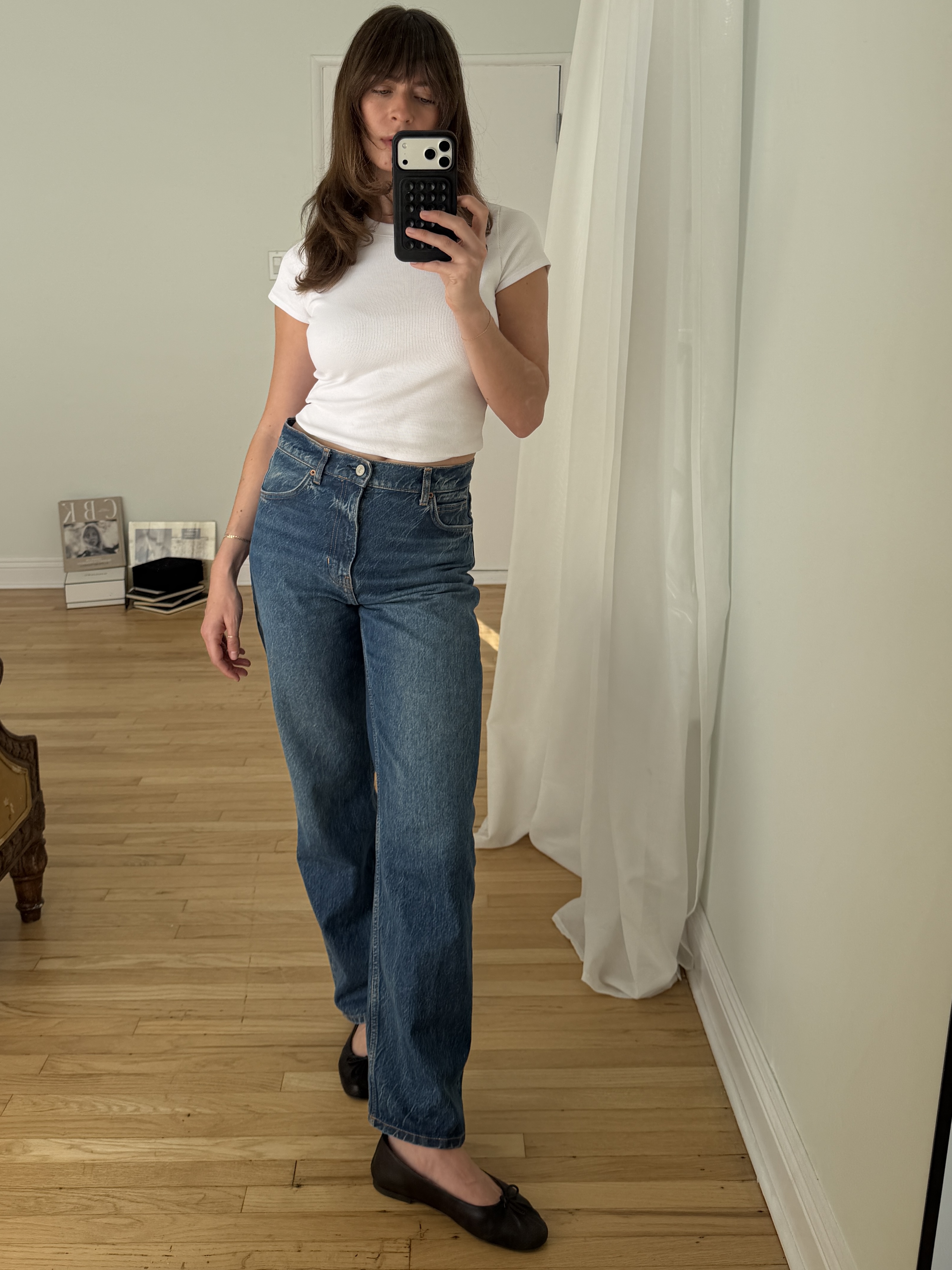 Kathryn Zahorak posing in mirror wearing white t-shirt, jeans, and black ballet flats 
