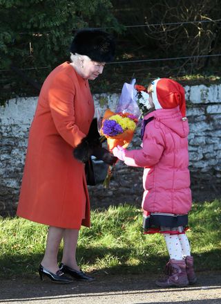 Queen Elizabeth accepts flowers from child at Sandringham on Christmas Day 2013