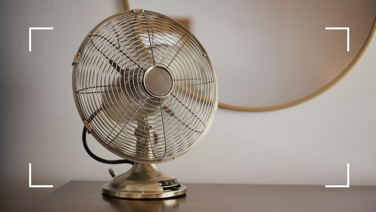  picture of electric fan on desk with a gold round mirro in the background to support the quesyton should you leave an electric fan on overnight