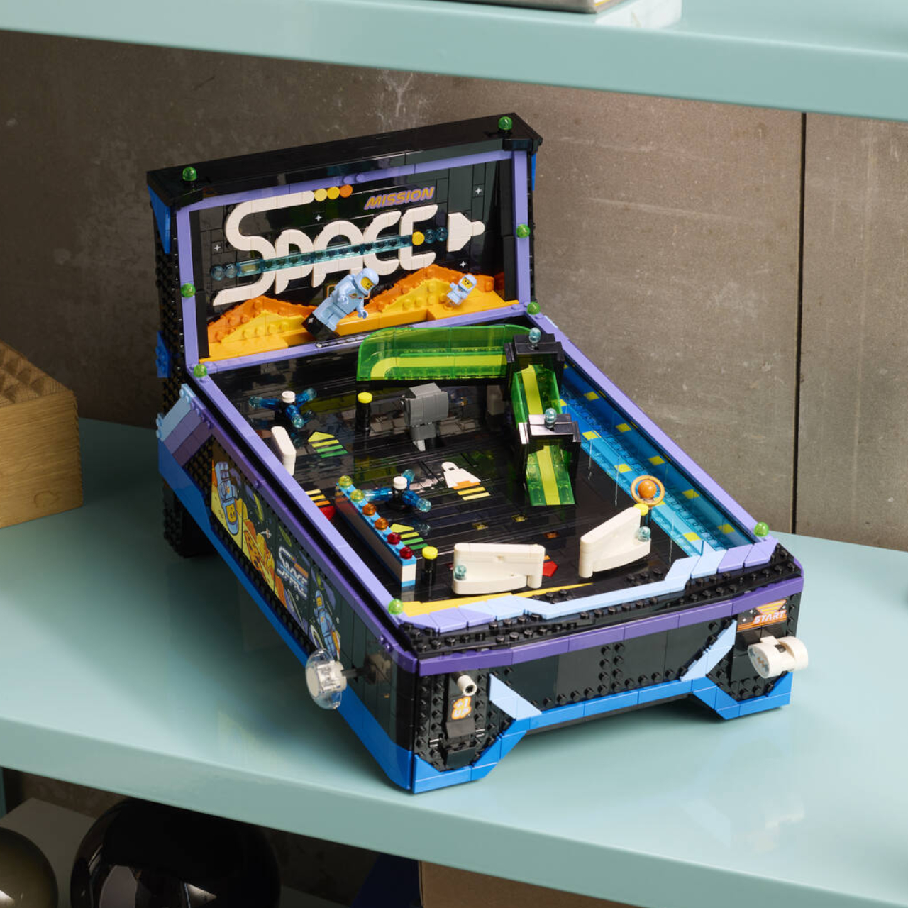 Lego Arcade Pinball Machine on a teal shelf, against a gray wall