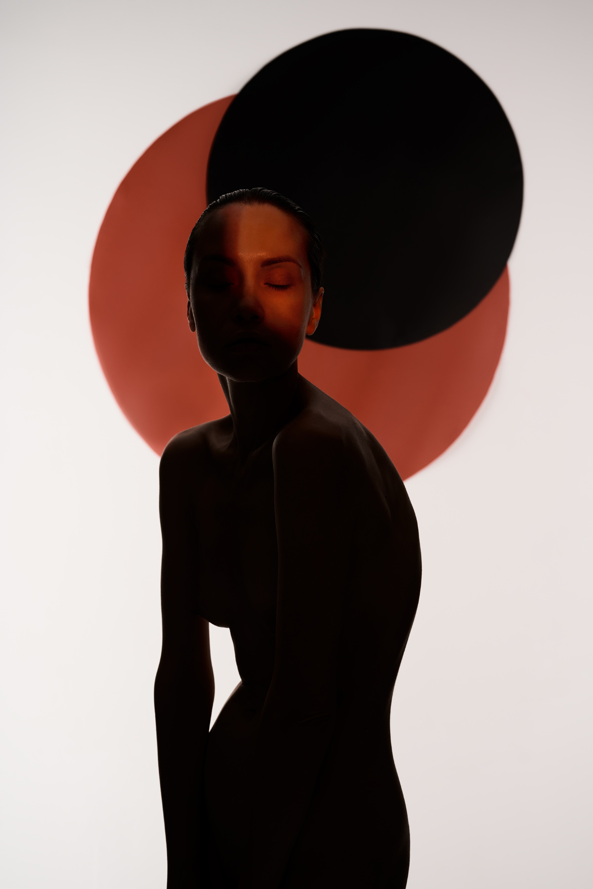 Woman standing in shadow in front of red and black circles