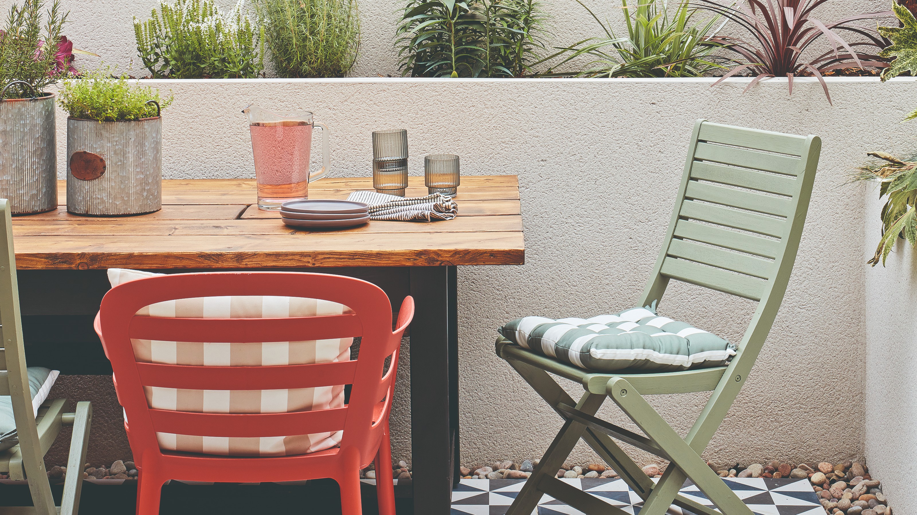 A patio with a wooden-top dining table and mis-matched chairs in green and burnt orange