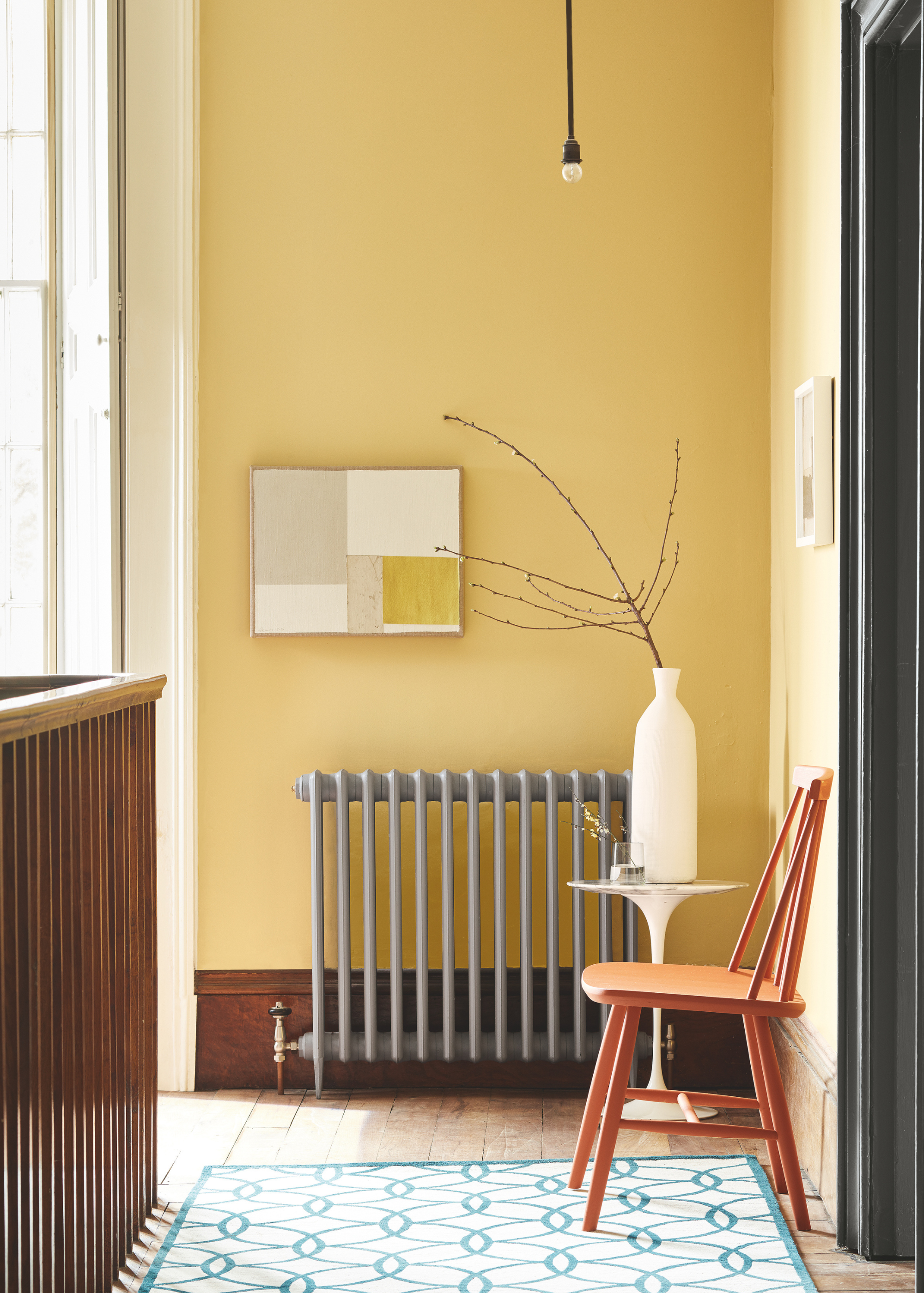 a muted grey/green radiator on a yellow wall in a hallway