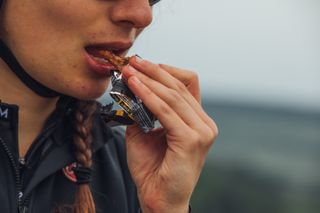 Female cyclist eating a sports nutrition energy bar on a bike ride