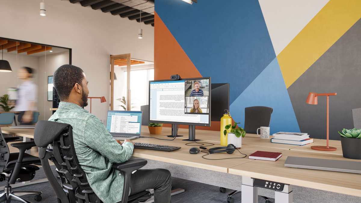 A man using a Logitech webcam and mouse in his office.