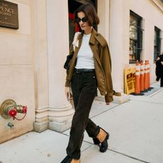 Woman in black jeans, white crewneck, and cropped trench. 