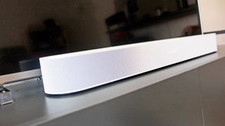 The Sonos Beam Gen 2 in white on a TV cabinet under a TV