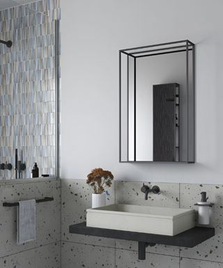 Modern industrial bathroom with terrazzo wall tiles, a sleek black floating vanity, and a rectangular vessel sink.