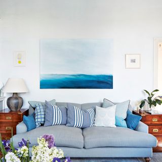 Living room with blue grey sofa, cushions and artwork