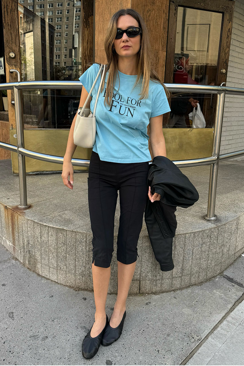 a woman wearing a blue tee, black capris and black flats