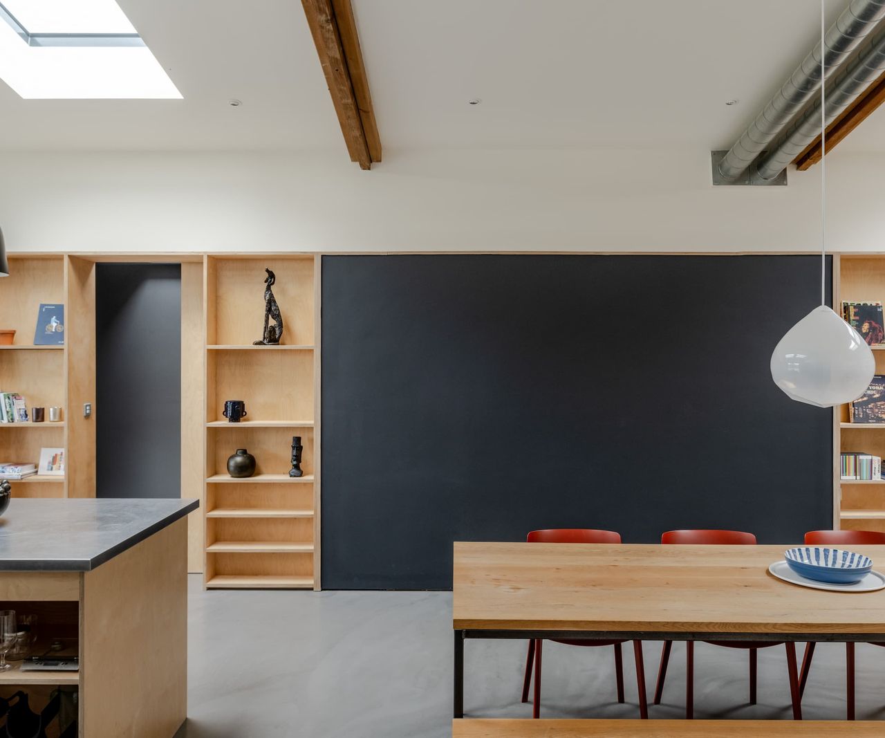 A dining area with a wooden dining table and wall storage areas