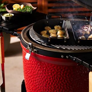 A red Kamado Joe egg-style bbq with open lid cooking food