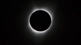 During the total solar eclipse, the Sun’s visible-light corona (meaning crown), only visible at maximum eclipse from within the path of totality, is seen here as a crown of white light extending from around the edge of the eclipsing Moon.