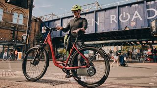 cyclist standing with bike fitted with Skarper e-bike conversion kit on the the camden road near to their office