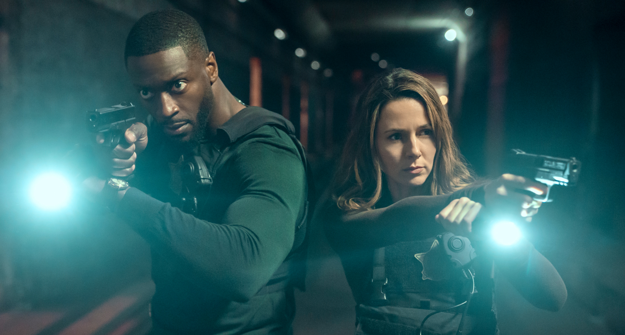 aldis hodge as alex cross and alona tal as kayla craig pointing guns and flash lights walking down a dark lit hallway in a still from cross season 2