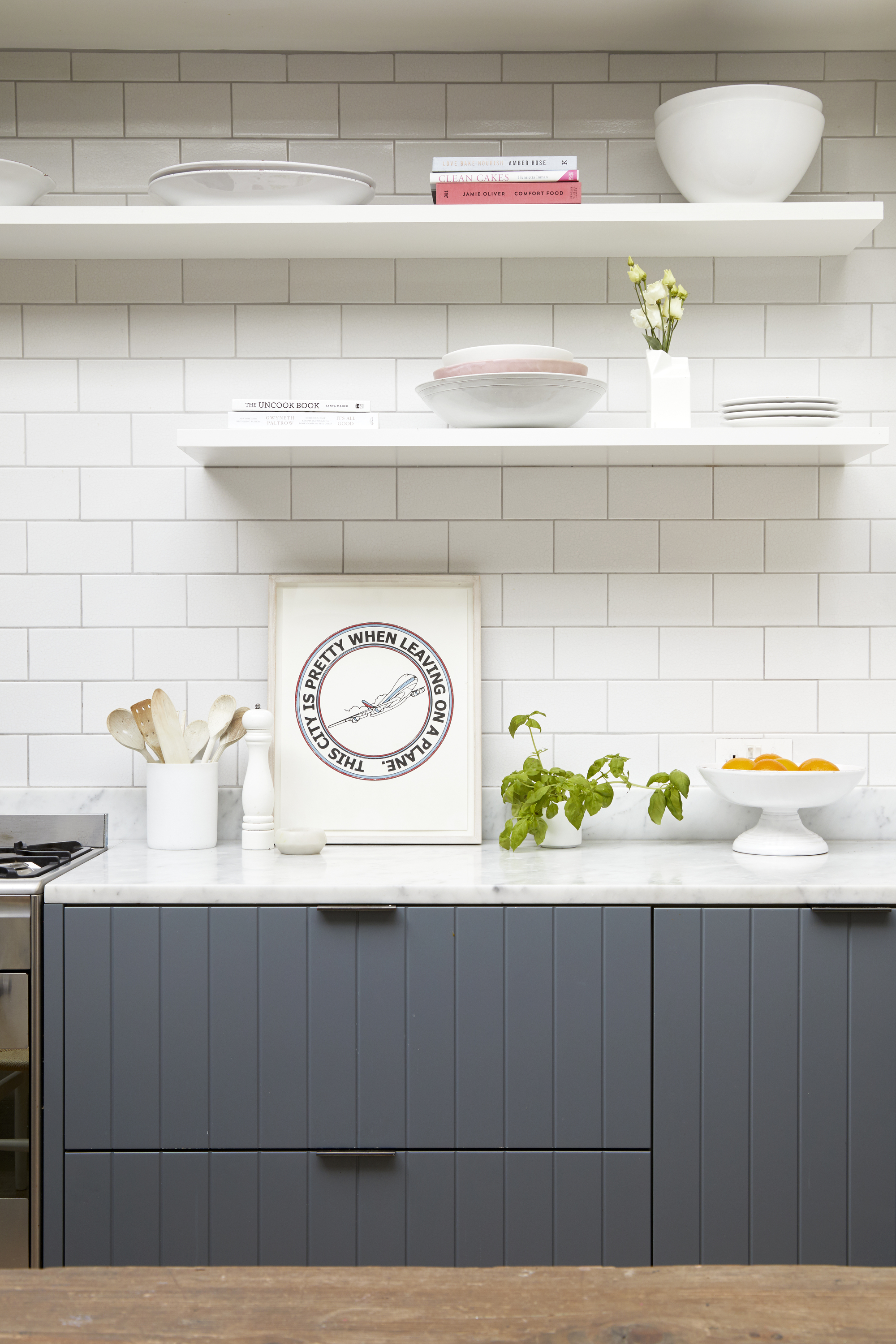 A kitchen with grey panelled cabinets and white countertops