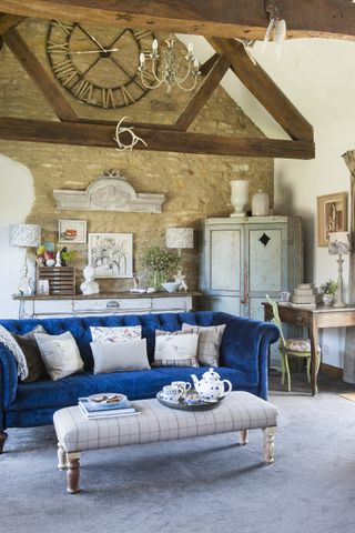 living_room_with_brick_wall_desk_blue_sofa_beamed_walls_footstool