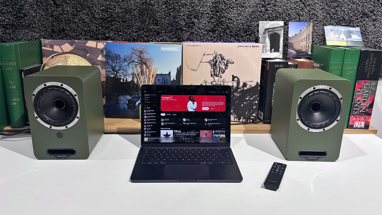 Fyne Audio Cubitt 5 speakers in olive green finish, placed on white table with records in background