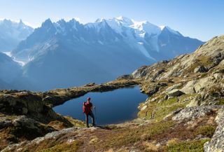 A hiker looks out at a lake and Mont Blanc