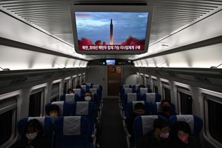 Commuters sit on a train under a television showing a news broadcast with file footage of a North Korean missile test, on the outskirts of Seoul on Nov. 2, 2022.