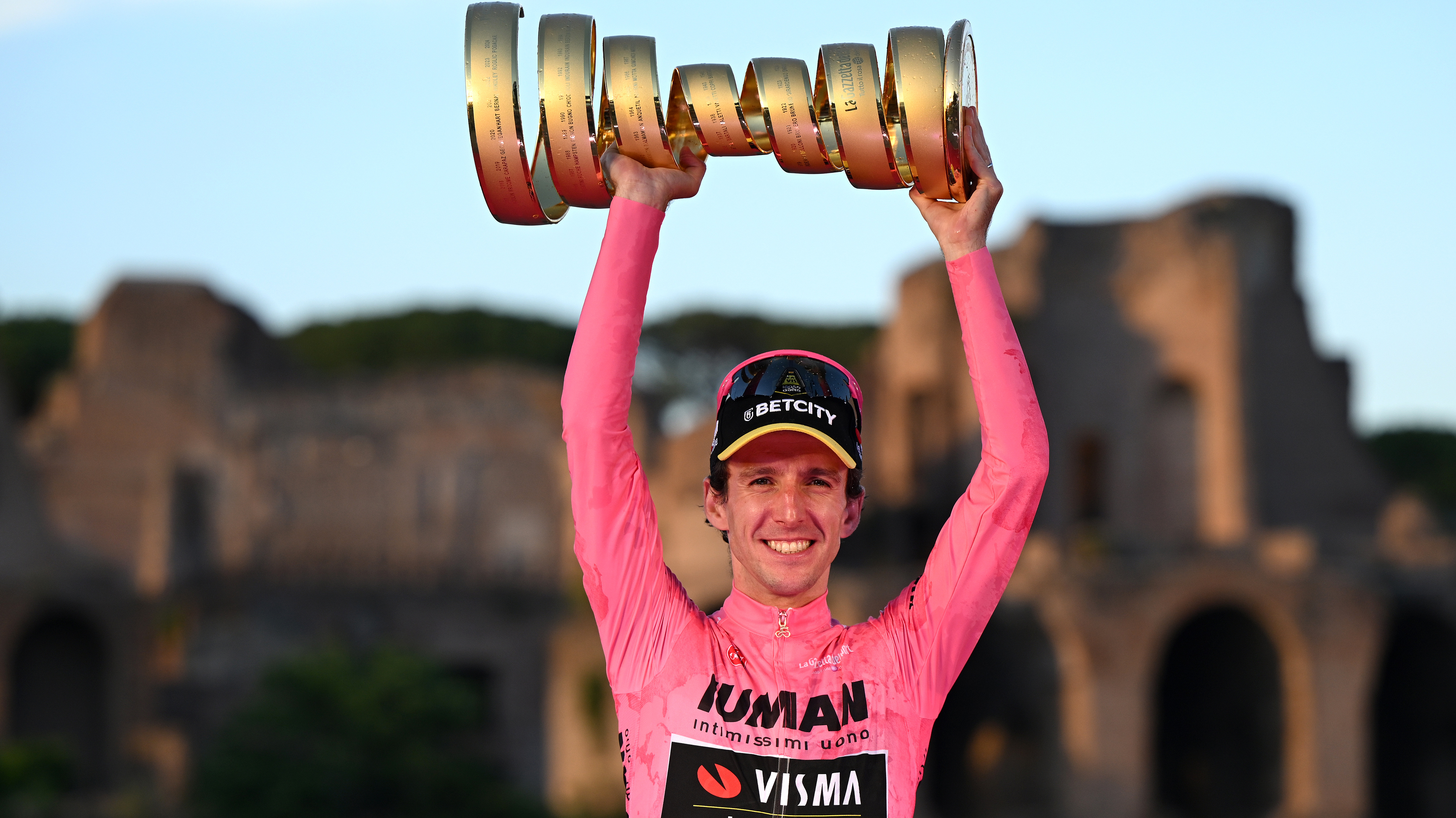 Simon Yates (Visma Lease a Bike) celebrates at podium as Pink Leader Jersey winner with the Trofeo Senza Fine during the 2025 Giro d'Italia