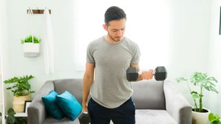 Man performs single dumbbell biceps curl at home