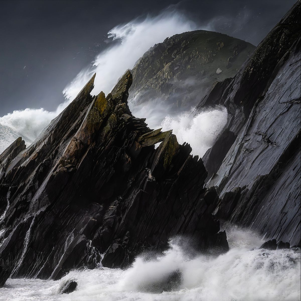 A landscape photograph of waves crashing against craggy rocks during a storm on the County Kerry coast in Ireland.