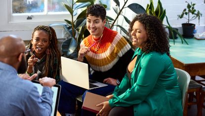 Four young adults interacting in an office environment.