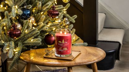 Yankee Candle Big Apple Christmas candle on table in front of Christmas tree