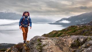 Man hiking in mountains with Garmin InReach Mini 2 device