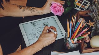 Tattoo art digital process on ipad. Tattoo artist hands holding Apple Pencil and drawing on iPad Pro in Procreate