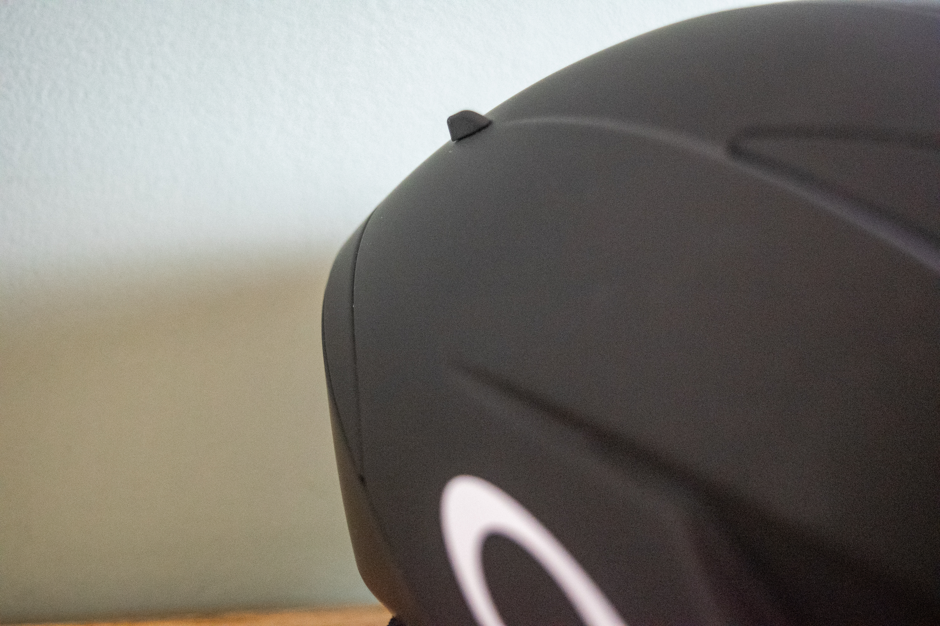 A rider wearing a black Oakley Velo Mac helmet in front of a green wall