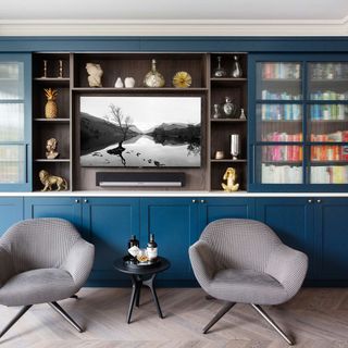 shelving unit with tv and reeded glass cabinets with two chairs and a side table