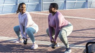 Two women using kettlebells on street