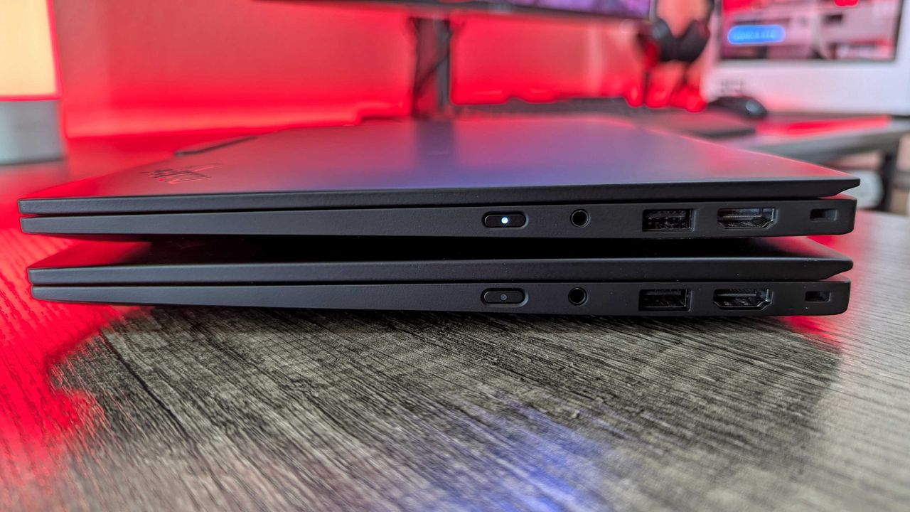 The Lenovo ThinkPad X1 Carbon (Gen 13) Aura Edition sitting on top of the Gen 12, showing the HDMI 2.1 port, USB Type-A 3.2 Gen 1 port, 3.5mm audio jack, and power button.